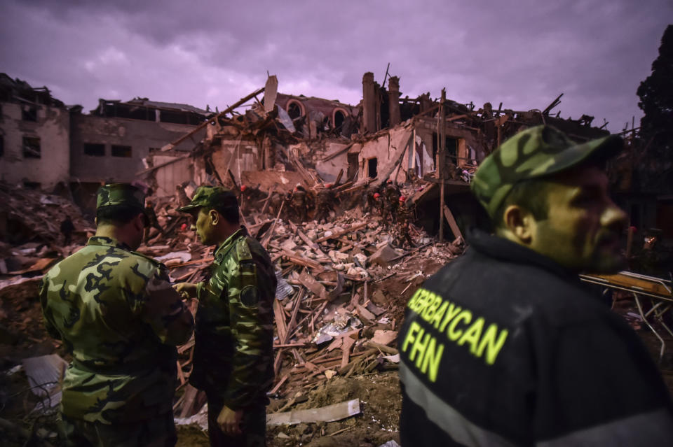 Soldiers and firefighters search for survivors in a residential area that was hit by rocket fire overnight by Armenian forces, early Sunday, Oct. 11, 2020, in Ganja, Azerbaijan's second largest city, near the border with Armenia. Several civilians were killed and dozens were wounded. Russian President Vladimir Putin brokered a cease-fire on Friday in a series of calls with President Ilham Aliyev of Azerbaijan and Armenia's Prime Minister Nikol Pashinian.(Ismail Coskun/IHA via AP)