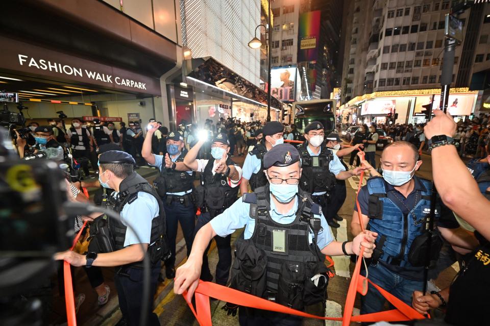 Police use cordon tape to control crowds in the Causeway Bay district of Hong Kong on June 4, 2022, near the venue where Hong Kong people have traditionally gathered to mourn victims of China's 1989 Tiananmen Square crackdown, on the 33rd anniversary of the event. - Hong Kong authorities strove to stop any public commemoration of the 33rd anniversary of the Tiananmen crackdown, with police warning gatherings could break the law as Beijing vies to remove all reminders of the events of June 4. (Photo by Peter PARKS / AFP) (Photo by PETER PARKS/AFP via Getty Images)