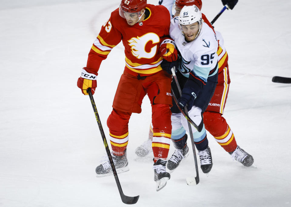 Seattle Kraken forward Andre Burakovsky, right, is checked by Calgary Flames forward Adam Ruzicka during the first period of an NHL hockey game, Tuesday, Nov. 1, 2022 in Calgary, Alberta. (Jeff McIntosh/The Canadian Press via AP)