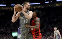 Sacramento Kings forward Domantas Sabonis, left, looks to pass the ball on Portland Trail Blazers forward Jabari Walker, right, during the first half of an NBA basketball game in Portland, Ore., Wednesday, March 29, 2023. (AP Photo/Steve Dykes)