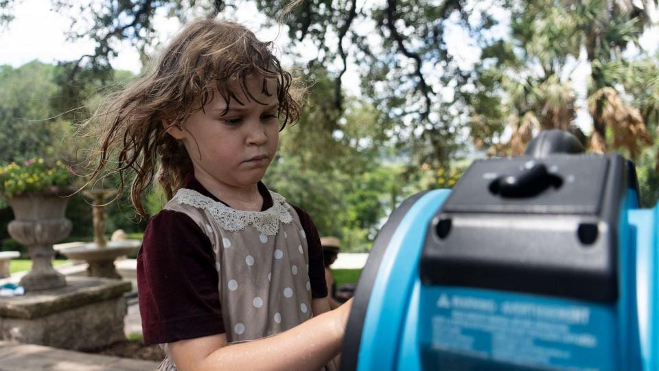 PHOTO: Aventurine Adams checks out a misting fan to cool off from the heat in Austin, Texas, July 8, 2023. (Austin American-Statesman via USA Today Network)