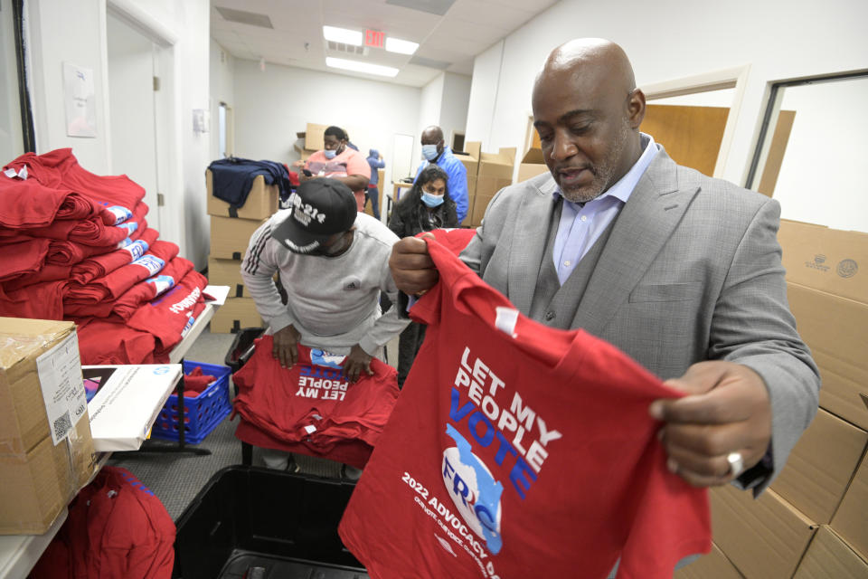 Desmond Meade looks at one of a stack of red T-shirts printed: Let My People Vote, FRRC, 2022 Advocacy.