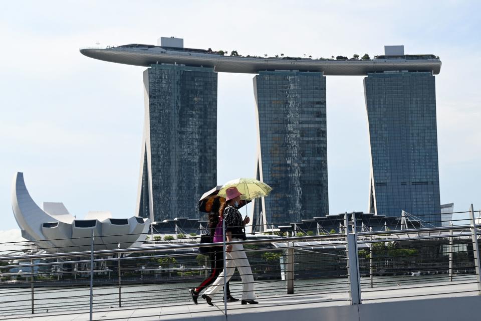 People seen walking across a bridge near the Marina Bay Sands integrated resort on 14 April, 2021. (PHOTO: AFP via Getty Images)