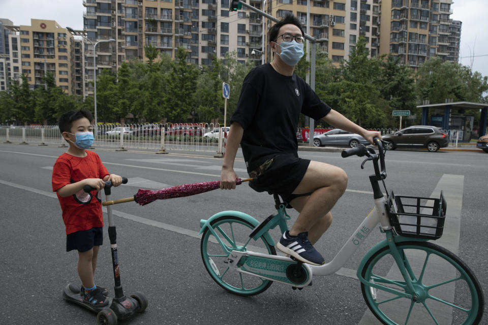 A man pulls a child along as they wear masks to curb the spread of the new coronavirus on the streets of Beijing, Saturday, May 30, 2020. (AP Photo/Ng Han Guan)