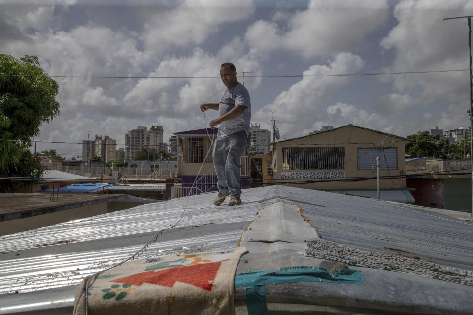 Jorge Ortiz works to tie down his roof as he prepares for the arrival of Tropical Storm Dorian, in the Martín Peña neighborhood of San Juan, Puerto Rico, Tuesday, Aug. 27, 2019. The 50-year-old construction worker was taking no chances as Dorian approached Puerto Rico on Tuesday and threatened to brush past the island's southwest coast at near-hurricane strength. (AP Photo/Gianfranco Gaglione)