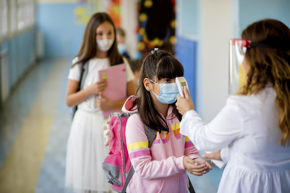 Teacher doing temperature check on school children