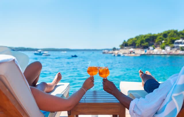 <p>Getty</p> stock image of a couple toasting a spritz on their honeymoon