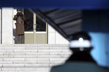 A North Korean soldier keeps watch as a South Korean soldier stands guard at the truce village of Panmunjom in the demilitarised zone separating the two Koreas, north of Seoul February 6, 2014. REUTERS/Han Jae-ho/News1