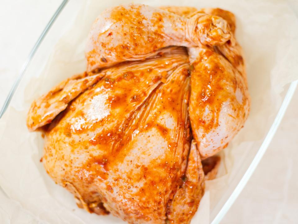 A whole turkey covered with an orange rub in a casserole dish