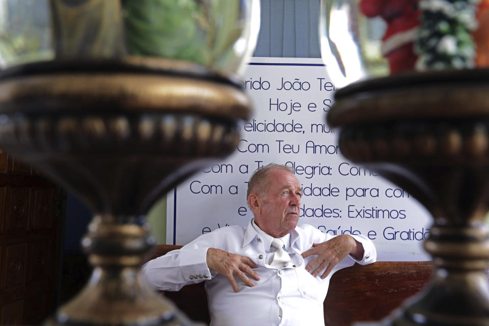 In this Jan. 4, 2019 photo, Norberto Kist talks in the lobby of his hostel in Abadiania, Brazil. Kist, who often assisted Brazilian spiritual healer Joao Teixeira de Faria, said the man he considered a "father" was attractive to women. "He had an energy," said Kist, waving his hands for emphasis. "And that generated fascination in women." (AP Photo/Eraldo Peres)