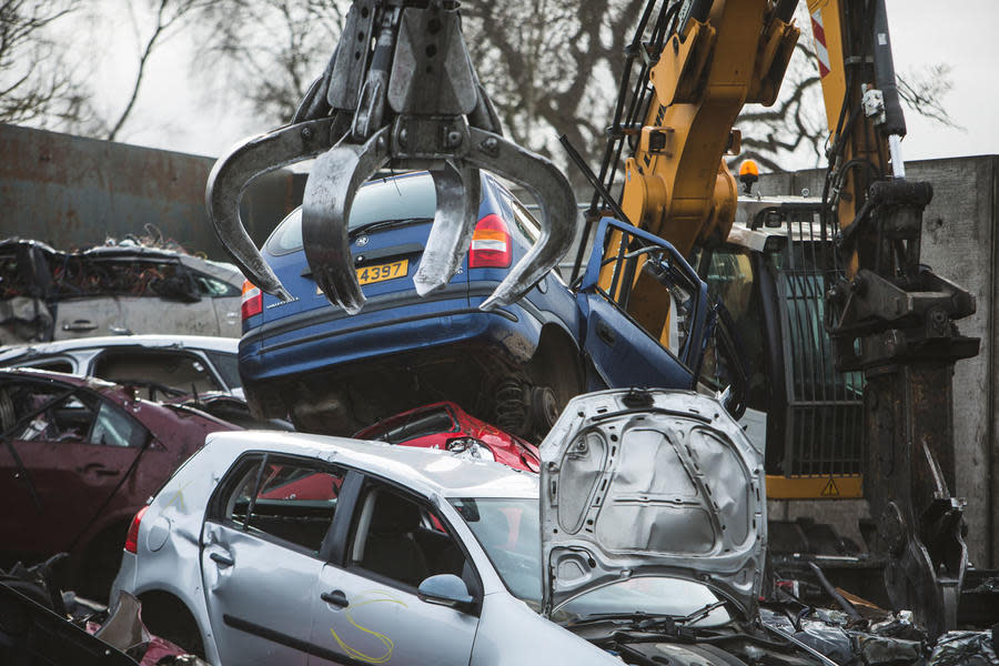 Blue Mk1 Vauxhall Zafira behind a crane in a scrapyard