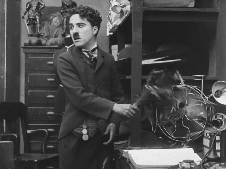 Charlie Chaplin performing a comedic scene in his film "The Pawnshop."