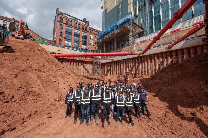Gary Neville, Director at Relentless Developments, with colleagues in hard hats and hi-vis clothing inside a giant hole in the ground in the centre of Manchester where a 41-storey tower will be built