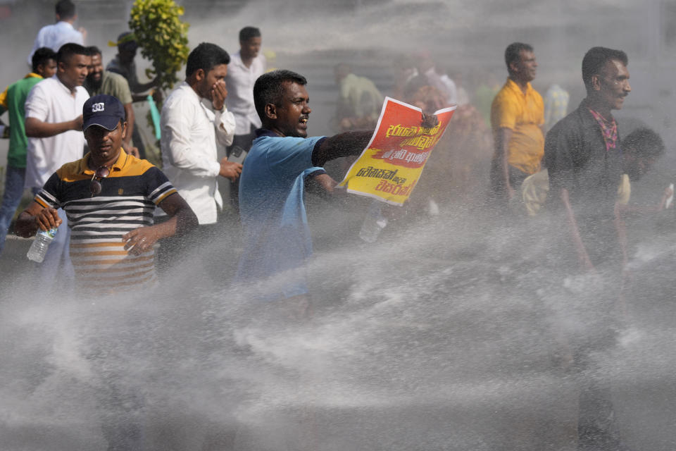 Supporters of Sri Lanka's main opposition shout slogans as police fire water cannons to disperse them during a protest rally against high taxes and increases in electricity and fuel charges, in Colombo, Sri Lanka, Tuesday, Jan. 30, 2024. (AP Photo/Eranga Jayawardena)