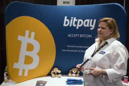 A woman explains how bitpay, a company designed to help companies use virtual currency, to an attendee during the