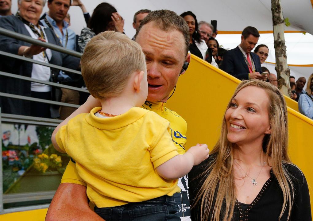 Tour de France winner Britain's Chris Froome, wearing the overall leader's yellow jersey, holds son Kellan as his wife Michelle looks on on the Champs Elysees avenue after the twenty-first and last stage of the Tour de France cycling race over 103 kilometers (64 miles) with start in Montgeron and finish in Paris, France, Sunday, July 23, 2017. (AP Photo/Thibault Camus)