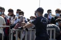 Migrants wait to enter a new temporary refugee camp in Kara Tepe,near Mytilene the capital of the northeastern island of Lesbos, Greece, Thursday, Sept. 17, 2020. Greek police are moving hundreds of migrants to an army-built camp on the island of Lesbos Thursday after a fire destroyed an overcrowded facility, leaving them homeless for days. (AP Photo/Petros Giannakouris)