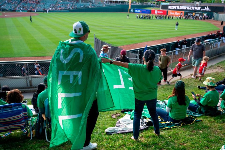 Last Dive Bar co-founder Bryan Johansen, left, wears a “SELL” flag during a protest Saturday at the River Cats game against the Las Vegas Aviators at Sutter Health Park.