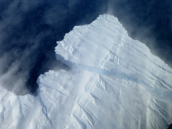 A nascent iceberg breaks off Pine Island Glacier's calving front. Icebergs in this area of the Amundsen Sea most often rise between 150 and 200 feet above the water surface. The image, taken from NASA's DC-8 on Nov. 4, 2012, also shows snow bei