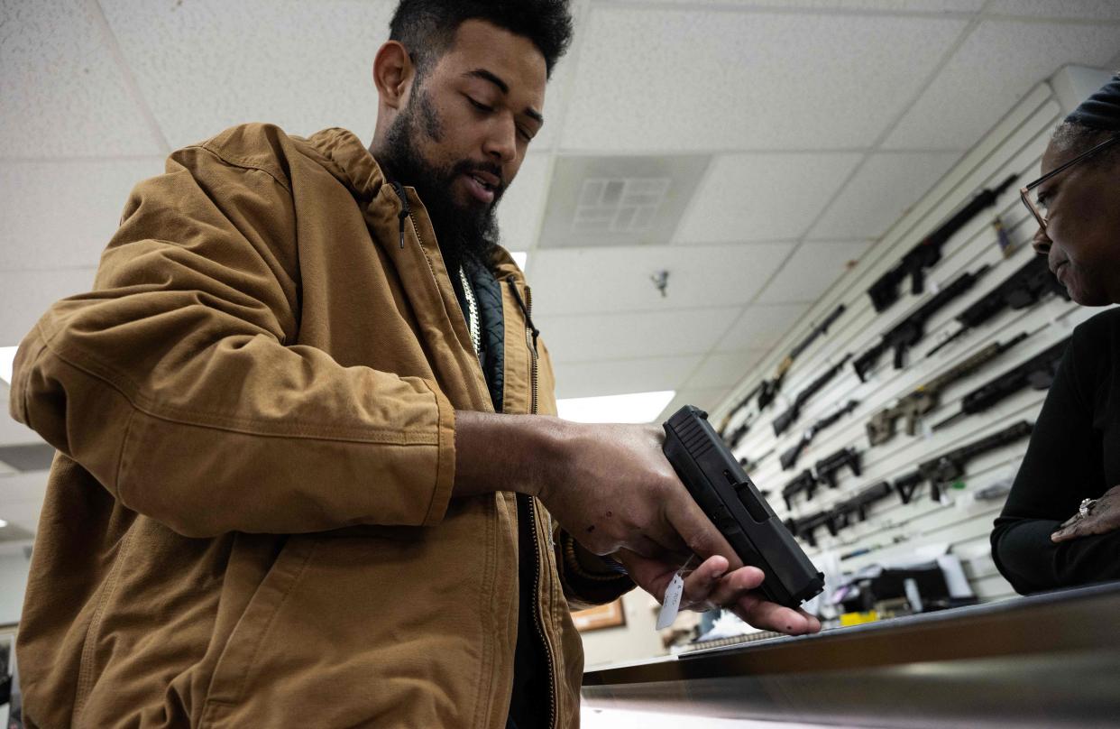 Jordan Landis, a Black gun collector, examines a pistol in a gun shop.