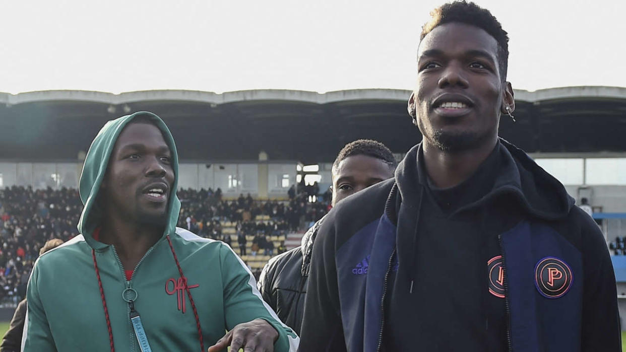 (FILES) This file photo taken on December 29, 2019 shows France national team player Paul Pogba (R) and his brother Mathias Pogba (L) walking on the pitch prior to a football match between All Star France and Guinea at the Vallee du Cher Stadium in Tours, central France, as part of the 