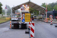 In this Saturday, June 13, 2020 photo, a sign with the opening hours of the border checkpoint between Harrislee in Germany and Padborg in Denmark is displayed in front the border crossing in Harrislee, Germany. Europe is taking a big step toward a new normality as many countries open up their borders to fellow Europeans after three months – but exceptions remain, and it remains to be seen how many will use their rediscovered freedom to travel. (Frank Molter/dpa via AP)