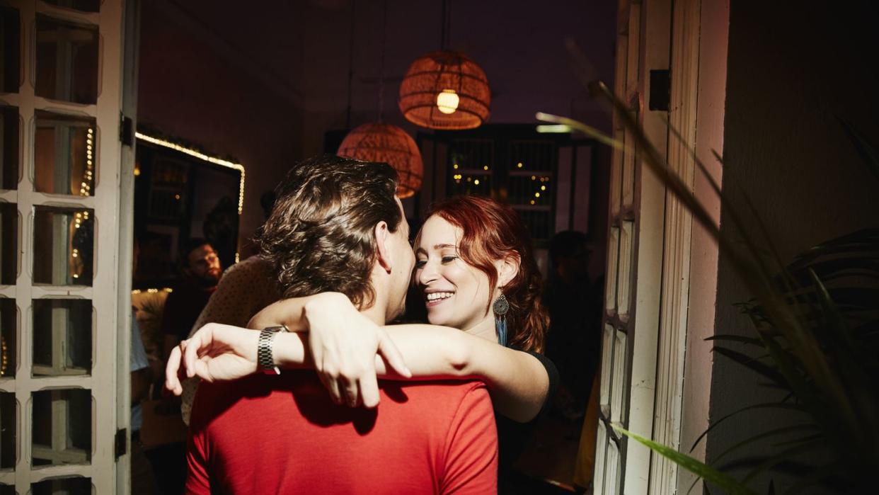 smiling woman embracing boyfriend during party in night club