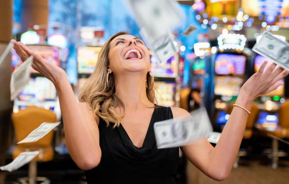 Cheerful beautiful woman excited about all the money she won at the casino throwing to the air very happy 