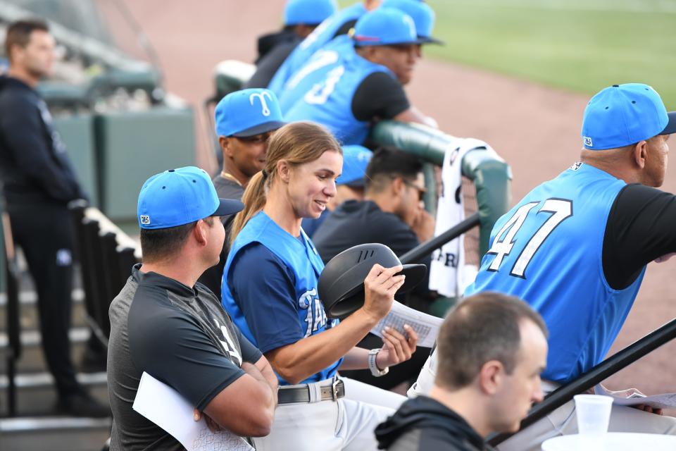 Rachel Balkovec inspects her batter's helmet in the Tampa Tarpons dugout. She's the first woman manager in the minors and pros.