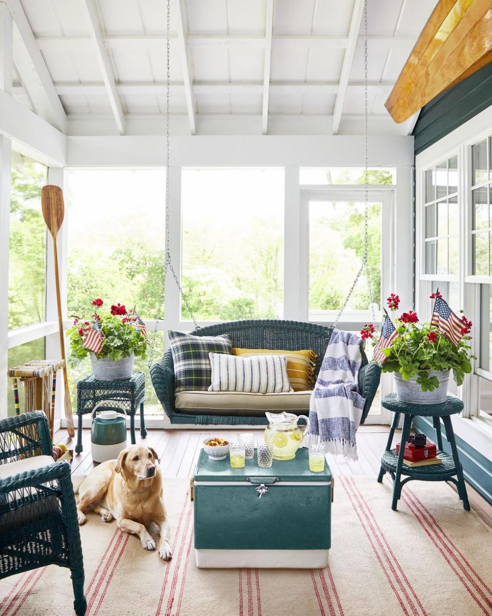 a screened porch with green wicker furniture