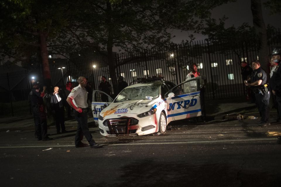 Policemen surround a NYPD vehicle after it was vandalized by protestors over the death of George Floyd, a black man who was in police custody in Minneapolis, on Saturday, May 30, 2020, in the Brooklyn borough of New York. Floyd died after being restrained by Minneapolis police officers on Memorial Day. (AP Photo/Wong Maye-E)