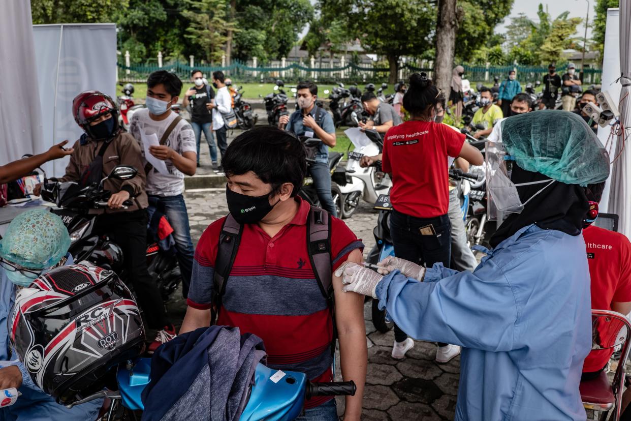 A healthcare worker administers a dose of the Sinovac Biotech Ltd. COVID-19 vaccine to a man on a motorcycle during a mass drive-thru vaccination program at the Prambanan temple complex on April 5, 2021, in Yogyakarta, Indonesia.