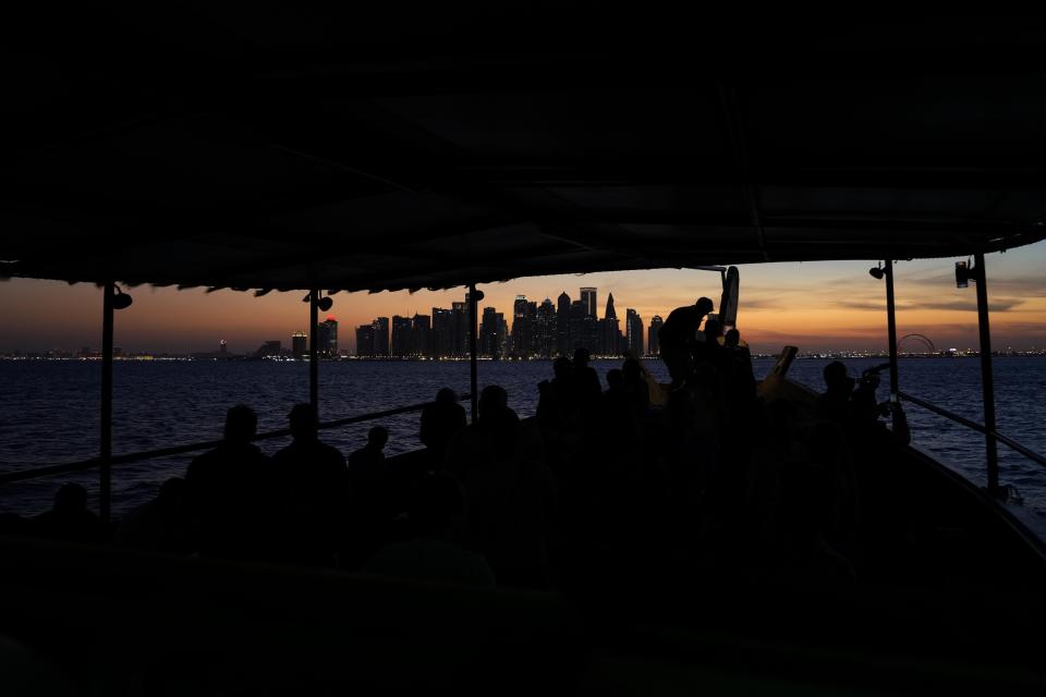 People sit on a boat as the sun sets over the West Bay skyline in Doha, Qatar, Monday, Nov. 28, 2022. (AP Photo/Matthias Schrader)