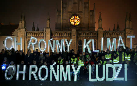 Environmental activists hold letters 'Save the climate, save the people' during the COP24 U.N. Climate Change Conference 2018 in front of the church in Imielin near Katowice, Poland, December 6, 2018