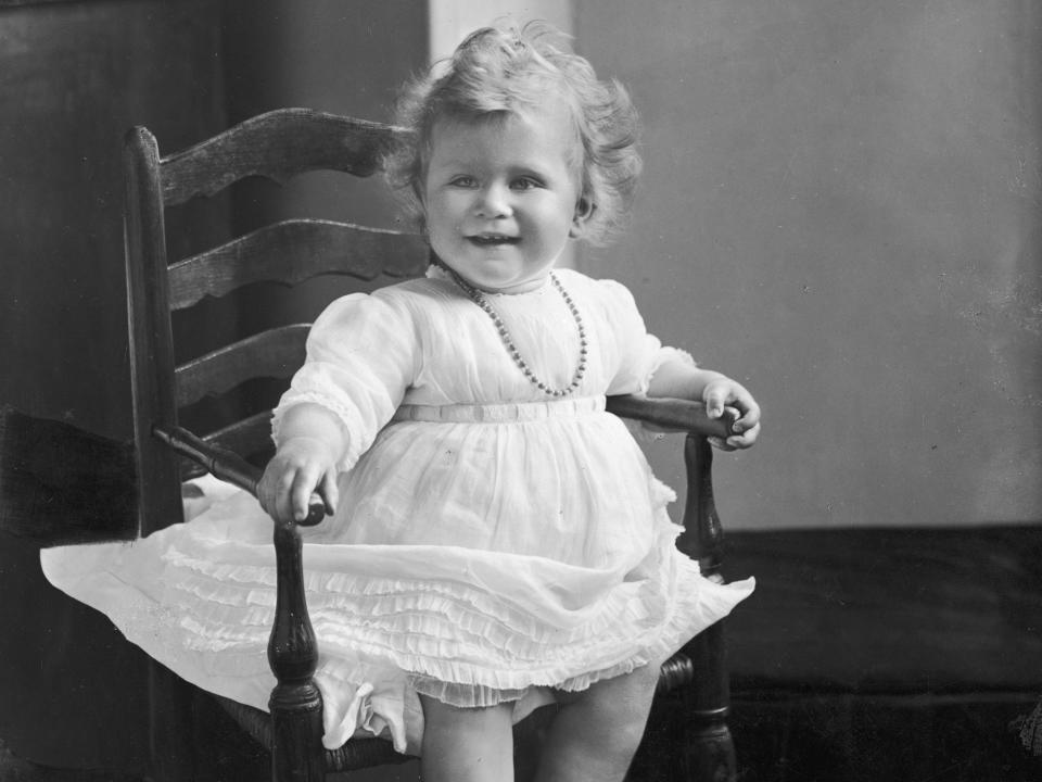 Baby Princess Elizabeth sits in a high chair in a puffy, white dress.