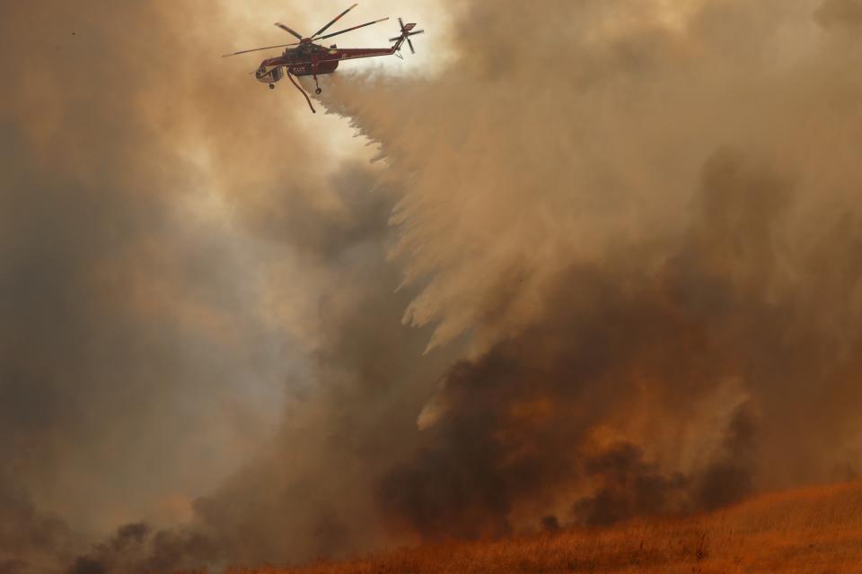 A helicopter drops water on a wind-driven wildfire in Orange, Calif., on Oct. 9, 2017.