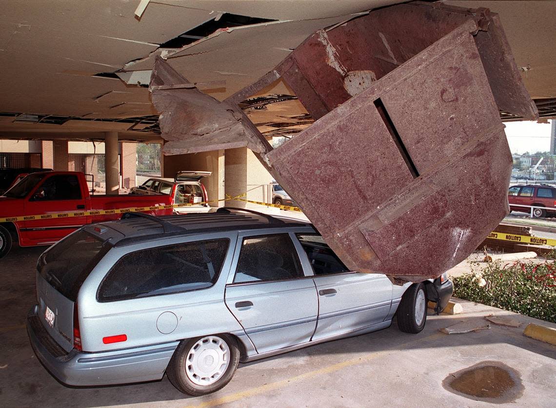 A large garbage bin is wedged between a station wagon and the roof of a parking garage at West Weatherford and Lexington streets, a block west of Henderson Street, after a tornado struck Fort Worth on March 28, 2000.