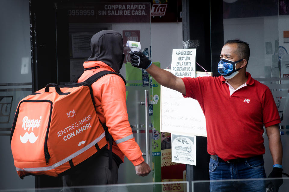 A guard at a store checks the temperature of a delivery driver in Quito, Ecuador, during the government lockdown to prevent the spread of COVID-19.<span class="copyright">Isadora Romero—Magnum Foundation</span>