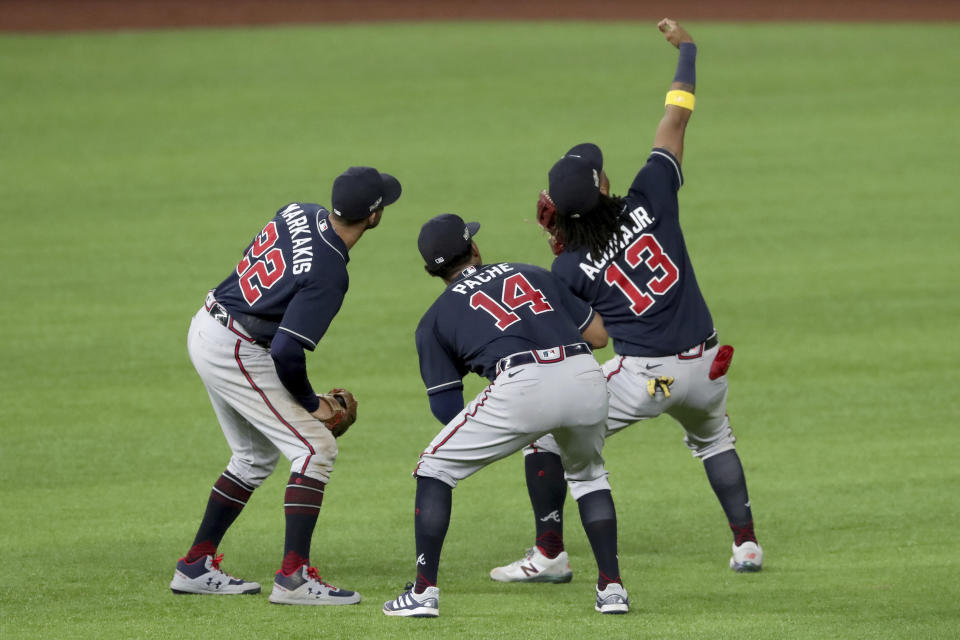 Atlanta Braves right fielder Ronald Acuna (13) takes a fake selfie with left fielder Nick Markakis, left, and center fielder Cristian Pache (14) after their win over the Los Angeles Dodgers in Game 2 Tuesday, Oct. 13, 2020, in the best-of-seven National League Championship Series at Globe Life Field in Arlington, Texas. (Curtis Compton/Atlanta Journal-Constitution via AP)