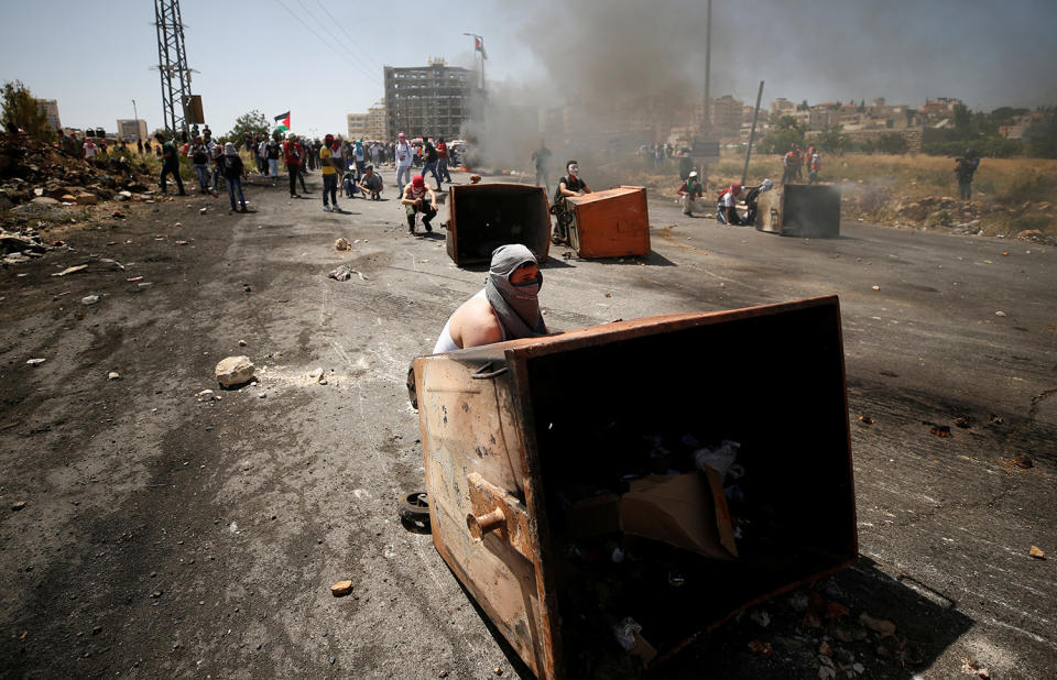 Palestinian protesters take cover during clashes in Ramallah