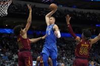 Dallas Mavericks forward Kristaps Porzingis (6) goes up to dunk between Cleveland Cavaliers' Jarrett Allen (31) and Isaac Okoro (35) in the first half of an NBA basketball game in Dallas, Monday, Nov. 29, 2021. (AP Photo/Tony Gutierrez)