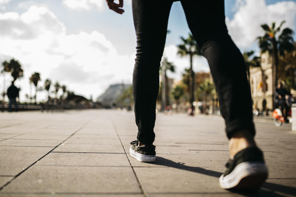 A person walking on pavement in sneakers