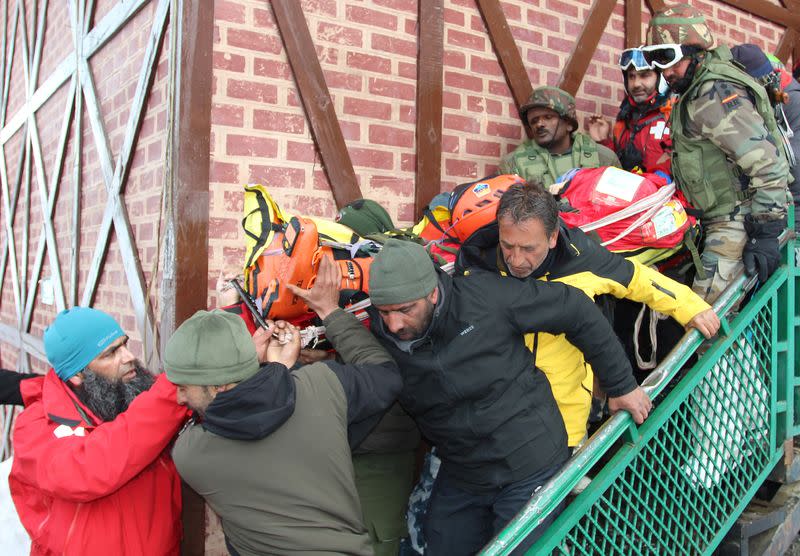 Security force personnel carry the body of a foreign skier, who was killed after an avalanche hit in the Affarwat area, in the ski resort of Gulmarg