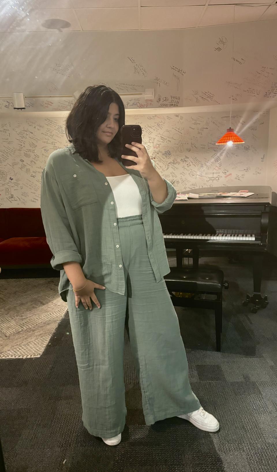 plus size Brunette woman taking mirror picture wearing light green Gap Crinkle Gauze Big Shirt and Mid Rise Pants with white t-shirt and white shoes