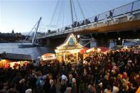 People shop at a Christmas market on the South Bank on the last Sunday before Christmas, in London December 22, 2013. REUTERS/Luke MacGregor