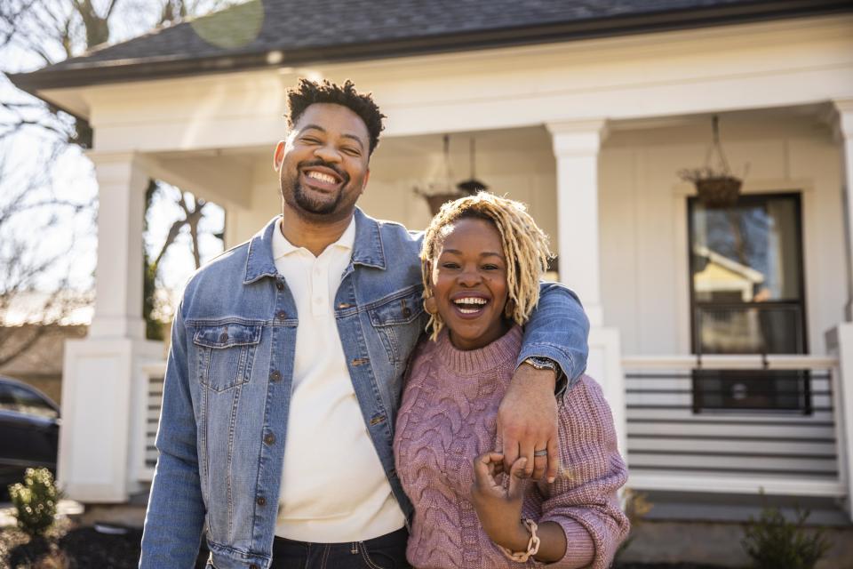 a happy duo stands in front of their home