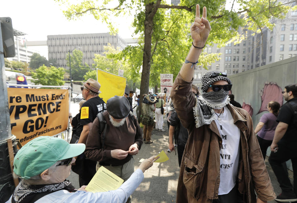 A protester holds up a peace sign while marching on the side of the street of anti-fascist groups counter-protesting as members of Patriot Prayer and other groups supporting gun rights demonstrate across the street during a rally, Saturday, Aug. 18, 2018, at City Hall in Seattle. (AP Photo/Ted S. Warren)