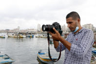 Palestinian journalist Hassan Slaieh makes video of fishermen at the sea port in Gaza City, Wednesday, Oct. 20, 2021. A hashtag for one of Islam's holiest sites banned. Scores of Palestinian journalist accounts blocked. Archives of the Syrian civil war disappeared. And a vast vocabulary of common words off-limits to speakers of Arabic, Facebook's third-most popular language with millions of users worldwide. (AP Photo/Adel Hana)