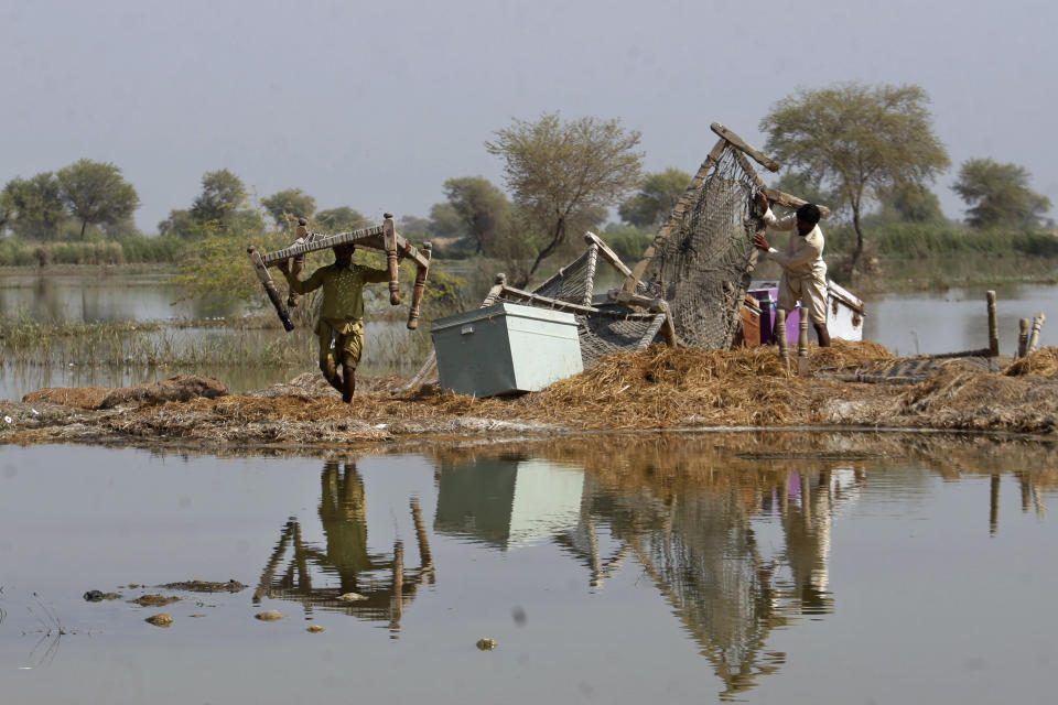 Villagers retrieve belongings they kept on the higher ground still surrounded by floodwaters in a village in Sohbat Pur, a flood-hit district of Baluchistan province, Pakistan, Oct. 25, 2022. Residents of Pakistan's poorest province, Baluchistan, say they are being neglected in recovery efforts after last summer's devastating floods. Around 75% of Baluchistan's population was affected by the flood, the highest proportion of any province in the country. (AP Photo/Fareed Khan)