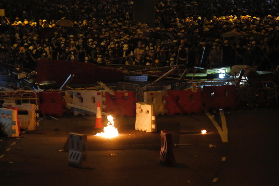 FILE - In this Wednesday, June 12, 2019, file photo, protesters gather behind barricade as a gasoline bomb thrown by a protester burns near the Legislative Council in Hong Kong. While police put up barriers to deter demonstrators, protesters built their own barricades to protect themselves, block roads and prevent lawmakers from reaching the legislature. Like their shields, the protesters' barricades are often repurposed materials, such as fences used to separate traffic lanes. (AP Photo/Kin Cheung, File)